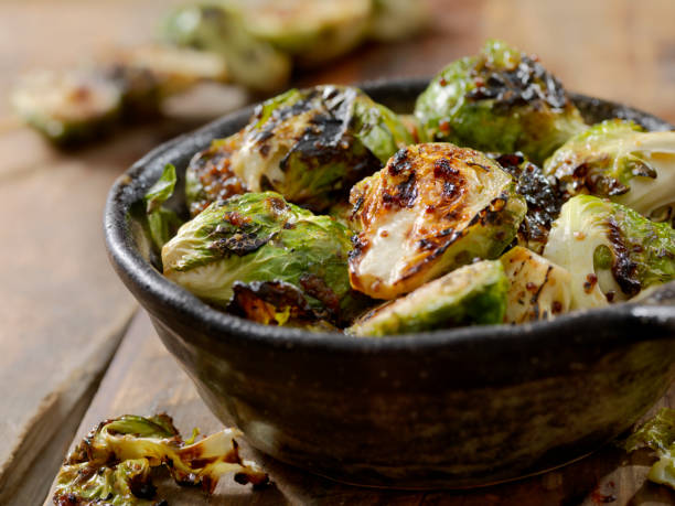 A bowl of charred Brussels sprouts on a wooden surface.