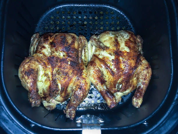 Two perfectly cooked whole chickens in an air fryer basket.