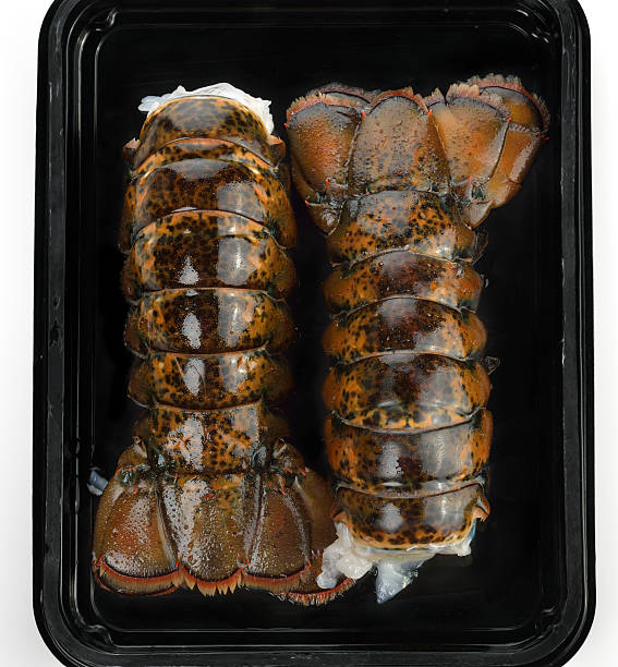 Two raw lobster tails displayed in a black plastic tray.