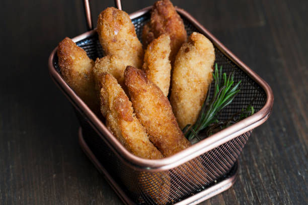 A basket filled with crispy golden fried food, garnished with a sprig of rosemary.