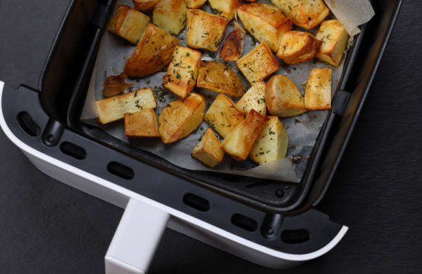 Crispy air-fried potatoes in an air fryer basket lined with parchment paper.