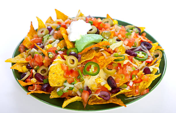 A large plate of colorful nachos topped with cheese, diced tomatoes, olives, jalapenos, and sour cream.