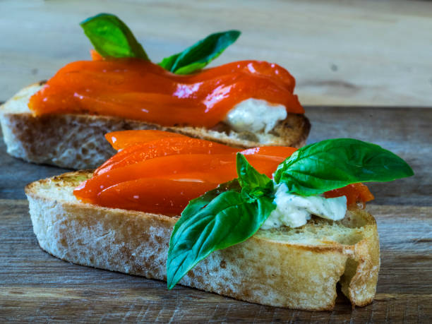 Bruschetta with roasted red peppers and basil on wooden background