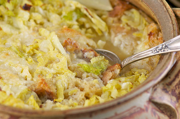 A close-up of a baked dish featuring layers of cooked cabbage and breadcrumbs with a serving spoon.