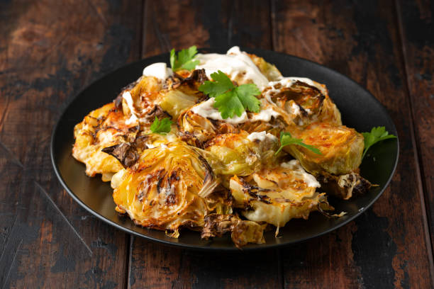 A plate of grilled cabbage topped with creamy sauce and garnished with fresh herbs.