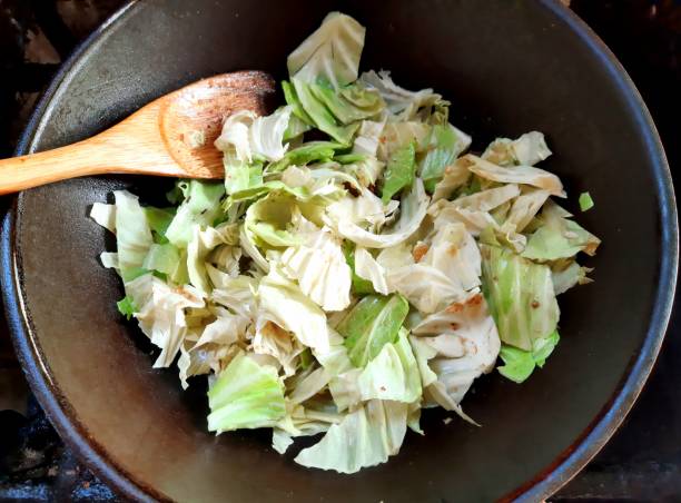 Chopped cabbage in a dark bowl with a wooden spoon