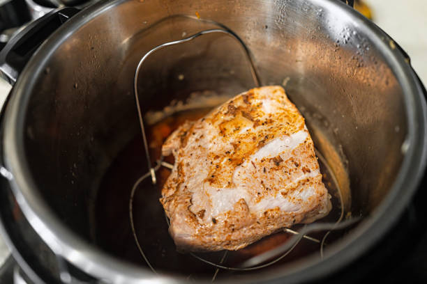 A piece of meat cooking in an Instant Pot with seasoning visible on the surface.