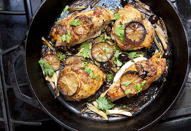 Pan-seared chicken breasts with lemon slices and herbs in a cast iron skillet.