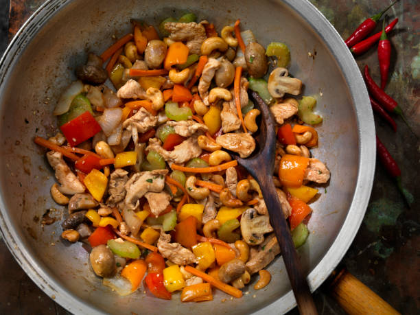 Stir-fried chicken with colorful vegetables and cashews in a metal pan