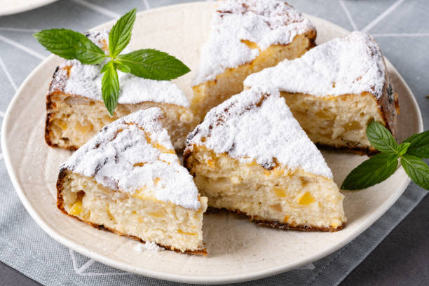 A plate of freshly baked scones dusted with powdered sugar and garnished with mint leaves.