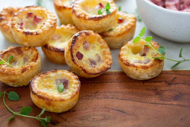 Delicious mini quiches arranged on a wooden board with fresh herbs.