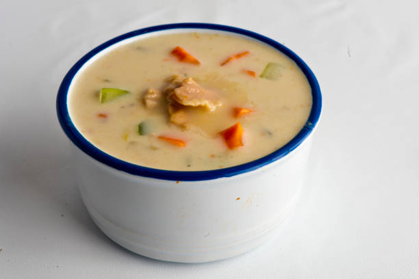 A bowl of creamy soup with chunks of chicken and mixed vegetables including carrots and green beans.