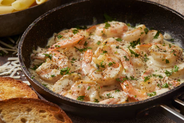 A pan of shrimp in creamy sauce garnished with parsley, served with slices of bread