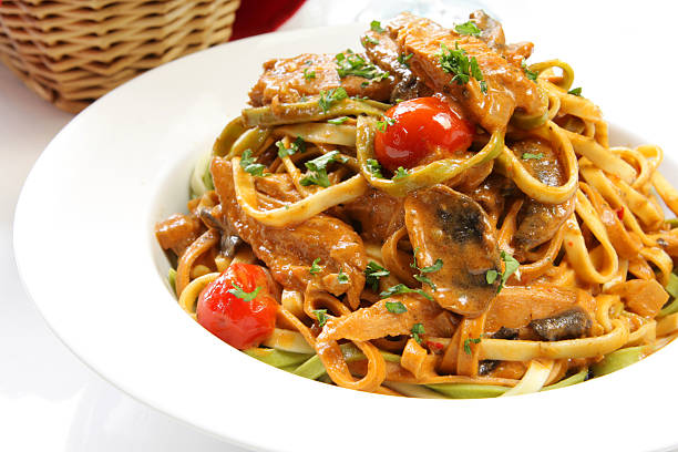 A delicious plate of fettuccine pasta with chicken, cherry tomatoes, and herbs.