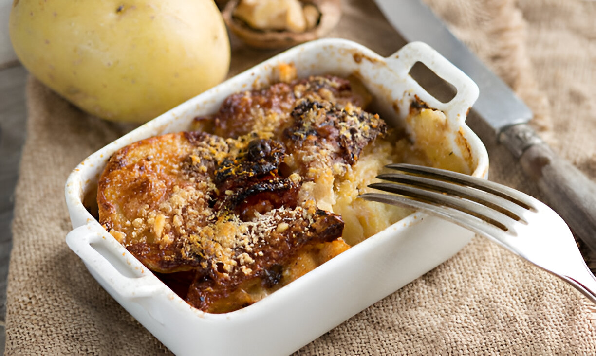 A serving of baked potato dish in a white casserole dish, topped with a golden, crispy crust.