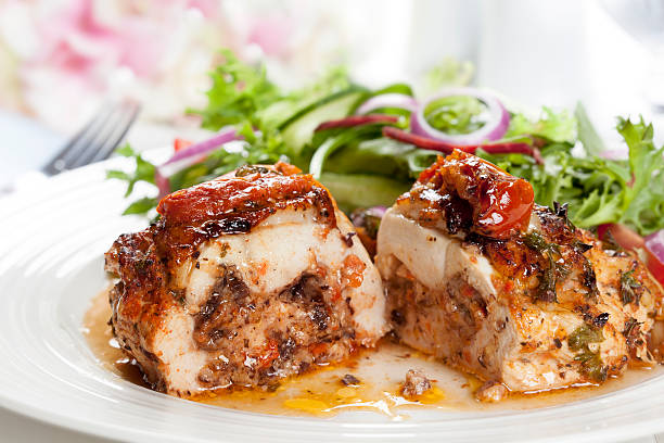 A plate featuring a portion of stuffed chicken breast, garnished with a fresh salad of mixed greens, cucumbers, and red onion.