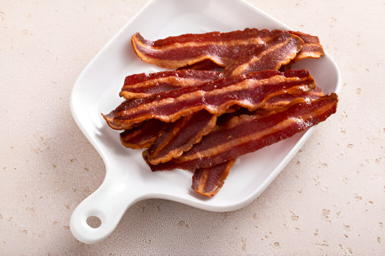 A plate of crispy bacon strips on a white dish