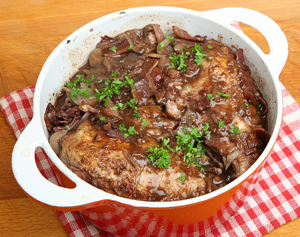 A dish of tender meat with gravy and garnished with fresh parsley, served in a white casserole dish.