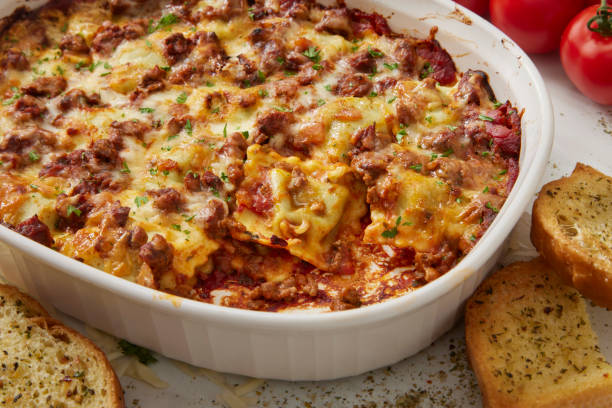 A deliciously baked lasagna topped with melted cheese and herbs, accompanied by slices of garlic bread.