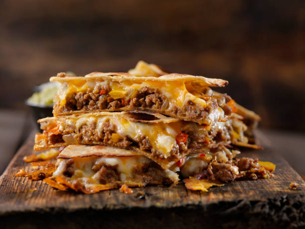 A stack of cheesy beef quesadillas on a wooden board