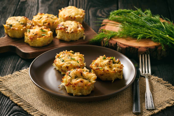 A plate of baked savory muffins garnished with herbs, surrounded by more muffins on a wooden table.