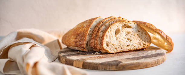 Freshly sliced sourdough bread on a wooden cutting board next to a linen napkin