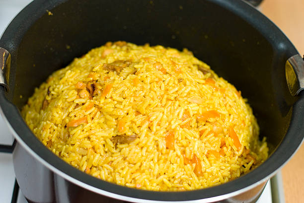 A pot filled with steaming yellow rice cooked with vegetables.