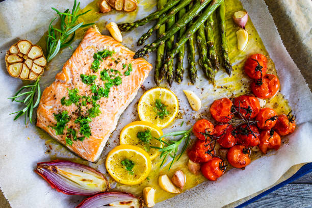 A beautifully arranged sheet pan meal featuring salmon, asparagus, tomatoes, and lemon slices.