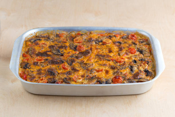 A baked dish with a golden brown top, dotted with cherry tomatoes, served in a silver rectangular pan.