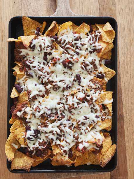 A tray of nachos topped with melted cheese, ground beef, and kidney beans.