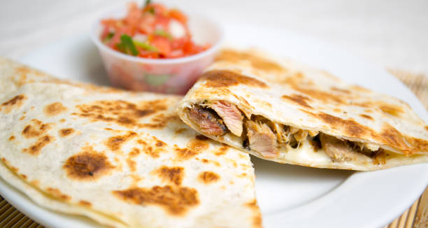 Delicious grilled quesadilla with meat and a side of fresh salsa.