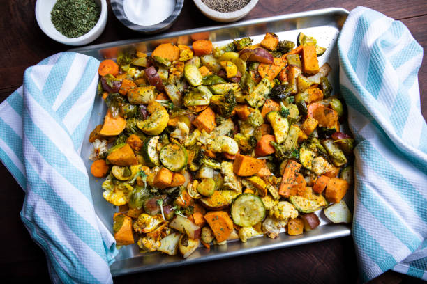 A colorful tray of roasted vegetables including carrots, zucchini, and sweet potatoes, garnished with herbs.