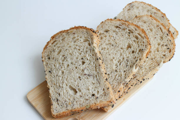 Slices of whole grain bread with seeds on a wooden cutting board.