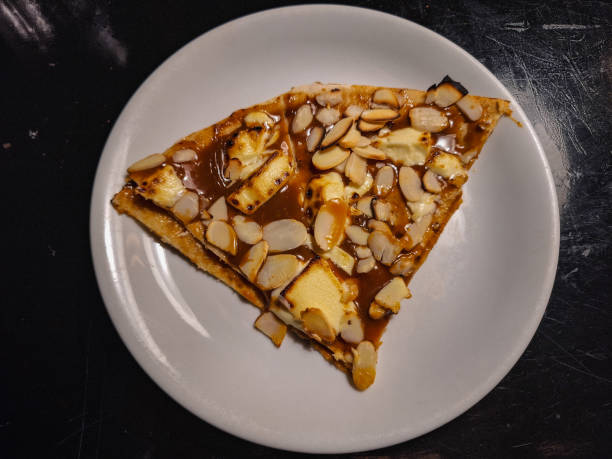 A slice of dessert featuring a caramelized topping with almond slices on a white plate.