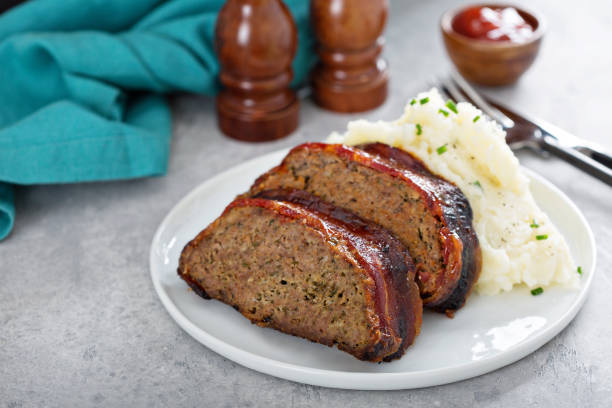 Sliced meatloaf served with creamy mashed potatoes on a white plate.