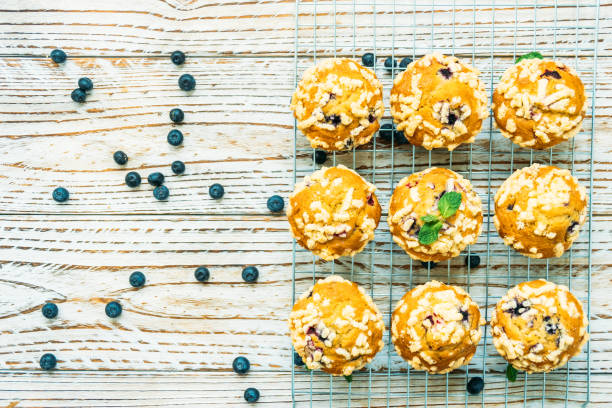 Freshly baked blueberry muffins on a wire rack with scattered blueberries around them