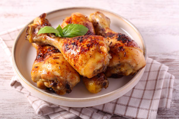 A plate of grilled chicken drumsticks garnished with fresh basil leaves