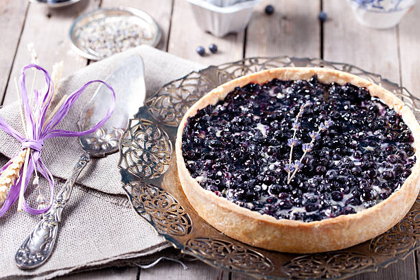 A beautifully baked blueberry pie on a decorative plate with a vintage fork and spoon beside it.