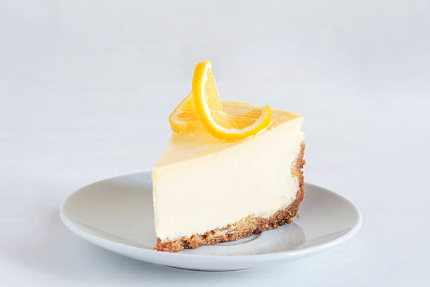 A slice of creamy lemon cheesecake topped with a lemon slice on a small plate.