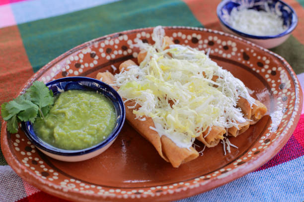 A traditional Mexican dish featuring rolled tortillas filled with a savory filling, topped with shredded cheese and accompanied by green salsa.