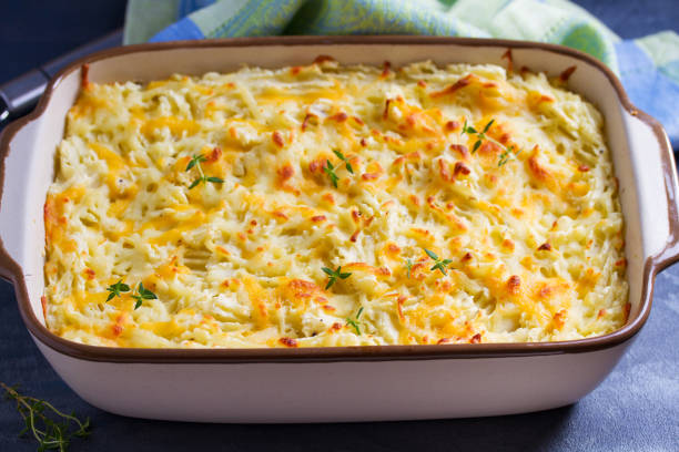 A creamy, cheesy baked potato dish topped with golden brown crust and garnished with fresh thyme.