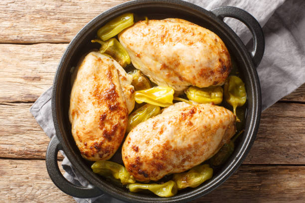 Three golden brown chicken breasts cooked with green peppers in a black cast iron skillet