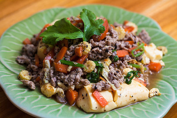 A vibrant dish featuring ground meat, tofu, and vegetables on a green plate.