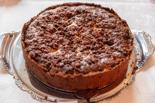 A round cake topped with a crumbly chocolate layer on a silver platter.