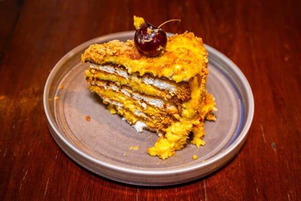 A slice of layered cake topped with a cherry on a gray plate.