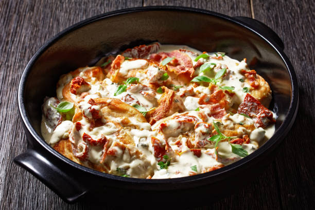 A delicious dish featuring creamy sauce, crispy bacon, and herbs served in a black casserole dish.