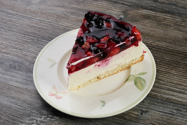 A slice of berry cheesecake with a glossy fruit topping on a decorative plate.