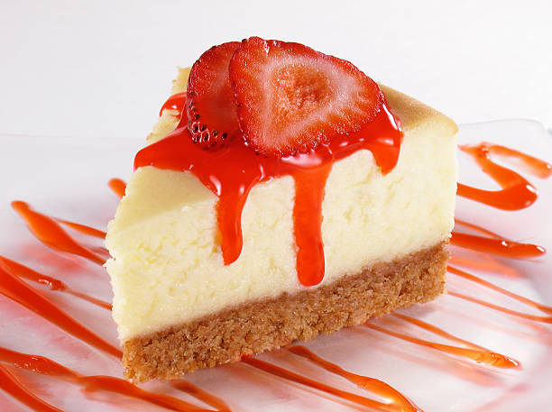 Slice of cheesecake topped with strawberries and red sauce