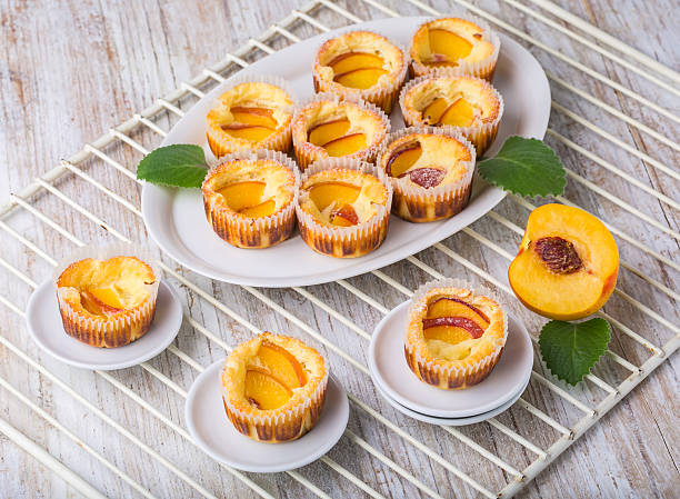 Mini peach cheesecakes on a plate with fresh peach slices and mint leaves.