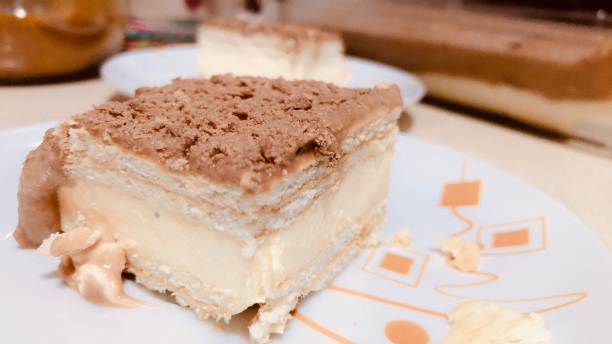 A slice of layered dessert on a plate, featuring a creamy filling and a crumbly topping.